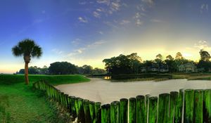 Preview wallpaper city, grass, trees, palm trees, buildings, fences, sand