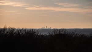 Preview wallpaper city, skyline, sunset, grass, fog