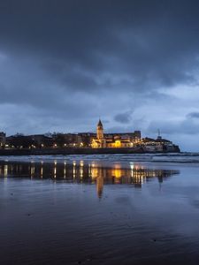 Preview wallpaper city, tower, sea, shore, clouds, reflection, dark