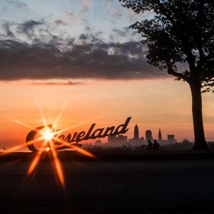 Preview wallpaper cleveland, night city, sunset, silhouettes, inscription, sunlight