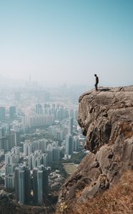 Preview wallpaper cliff, man, city, aerial view, height, loneliness