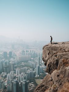 Preview wallpaper cliff, man, city, aerial view, height, loneliness