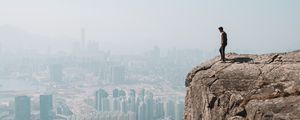 Preview wallpaper cliff, man, city, aerial view, height, loneliness