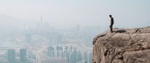 Preview wallpaper cliff, man, city, aerial view, height, loneliness