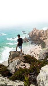 Preview wallpaper cliff, man, rocks, sea, beach, overview