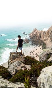 Preview wallpaper cliff, man, rocks, sea, beach, overview