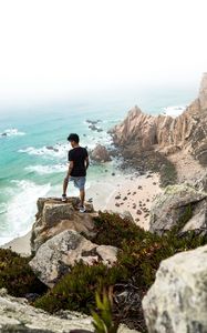 Preview wallpaper cliff, man, rocks, sea, beach, overview