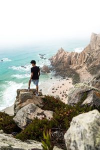 Preview wallpaper cliff, man, rocks, sea, beach, overview