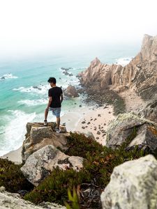 Preview wallpaper cliff, man, rocks, sea, beach, overview