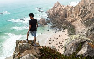 Preview wallpaper cliff, man, rocks, sea, beach, overview