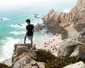 Preview wallpaper cliff, man, rocks, sea, beach, overview