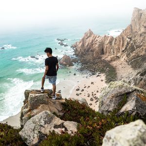 Preview wallpaper cliff, man, rocks, sea, beach, overview