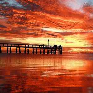 Preview wallpaper clouds, decline, evening, sky, orange, structure, pier, people, bridge, sea