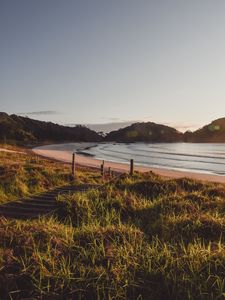 Preview wallpaper coast, hills, sea, stairs, grass, sky