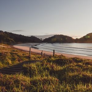 Preview wallpaper coast, hills, sea, stairs, grass, sky