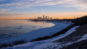 Preview wallpaper coast, lake, winter, snow, city, sunrise