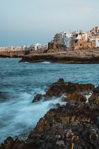 Preview wallpaper coast, rocks, sea, buildings, city