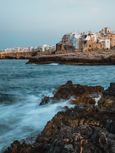 Preview wallpaper coast, rocks, sea, buildings, city