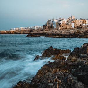 Preview wallpaper coast, rocks, sea, buildings, city