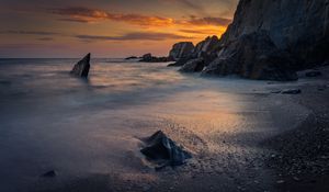 Preview wallpaper coast, sunset, rocks, sea, sand