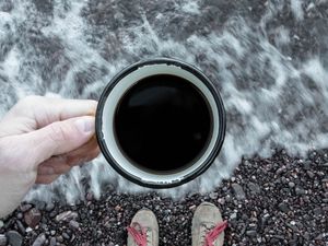 Preview wallpaper coffee, cup, legs, hand, pebbles, sea