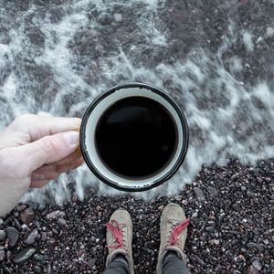 Preview wallpaper coffee, cup, legs, hand, pebbles, sea