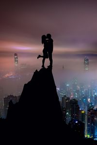 Preview wallpaper couple, silhouettes, kiss, hill, city, skyscrapers
