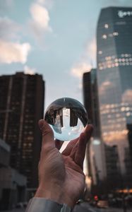 Preview wallpaper crystal ball, ball, hand, reflection, city, buildings