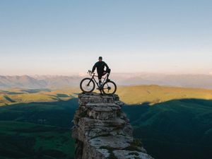 Preview wallpaper cyclist, bicycle, rock, peak, height