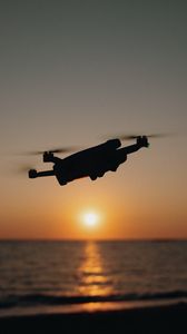 Preview wallpaper drone, silhouette, sea, glare, sky, sunset