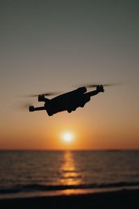 Preview wallpaper drone, silhouette, sea, glare, sky, sunset