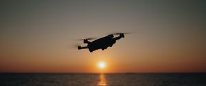 Preview wallpaper drone, silhouette, sea, glare, sky, sunset