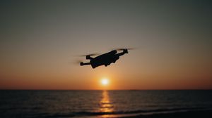 Preview wallpaper drone, silhouette, sea, glare, sky, sunset