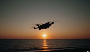 Preview wallpaper drone, silhouette, sea, glare, sky, sunset