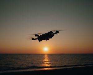 Preview wallpaper drone, silhouette, sea, glare, sky, sunset