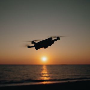 Preview wallpaper drone, silhouette, sea, glare, sky, sunset