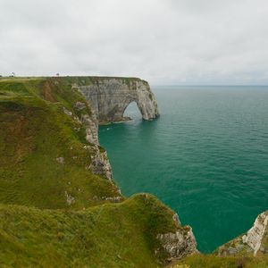 Preview wallpaper etretat cliffs, rocks, arch, sea, plants, clouds, nature, france