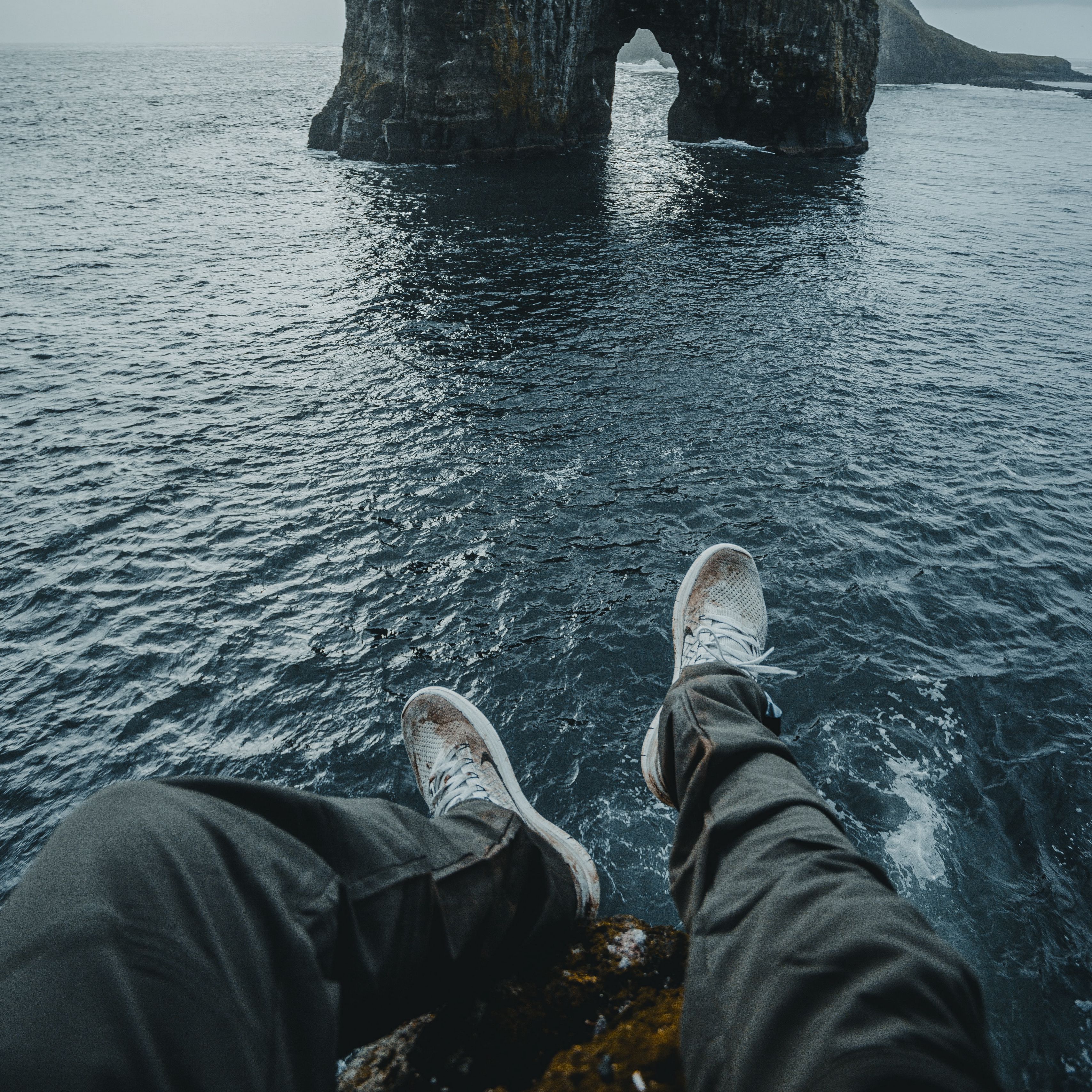 Ноги скалы. Фото скал под ногами. Подросток прыгает с высокой скалы в океан. Foot rock