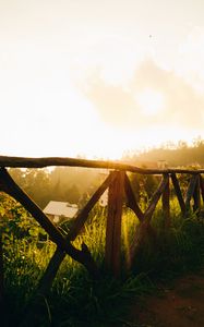 Preview wallpaper fence, grass, houses, trees, rays, sun, nature