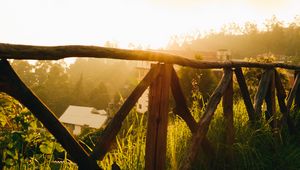 Preview wallpaper fence, grass, houses, trees, rays, sun, nature