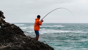 Preview wallpaper fishing, fisherman, boy, fishing rod, rock, sea