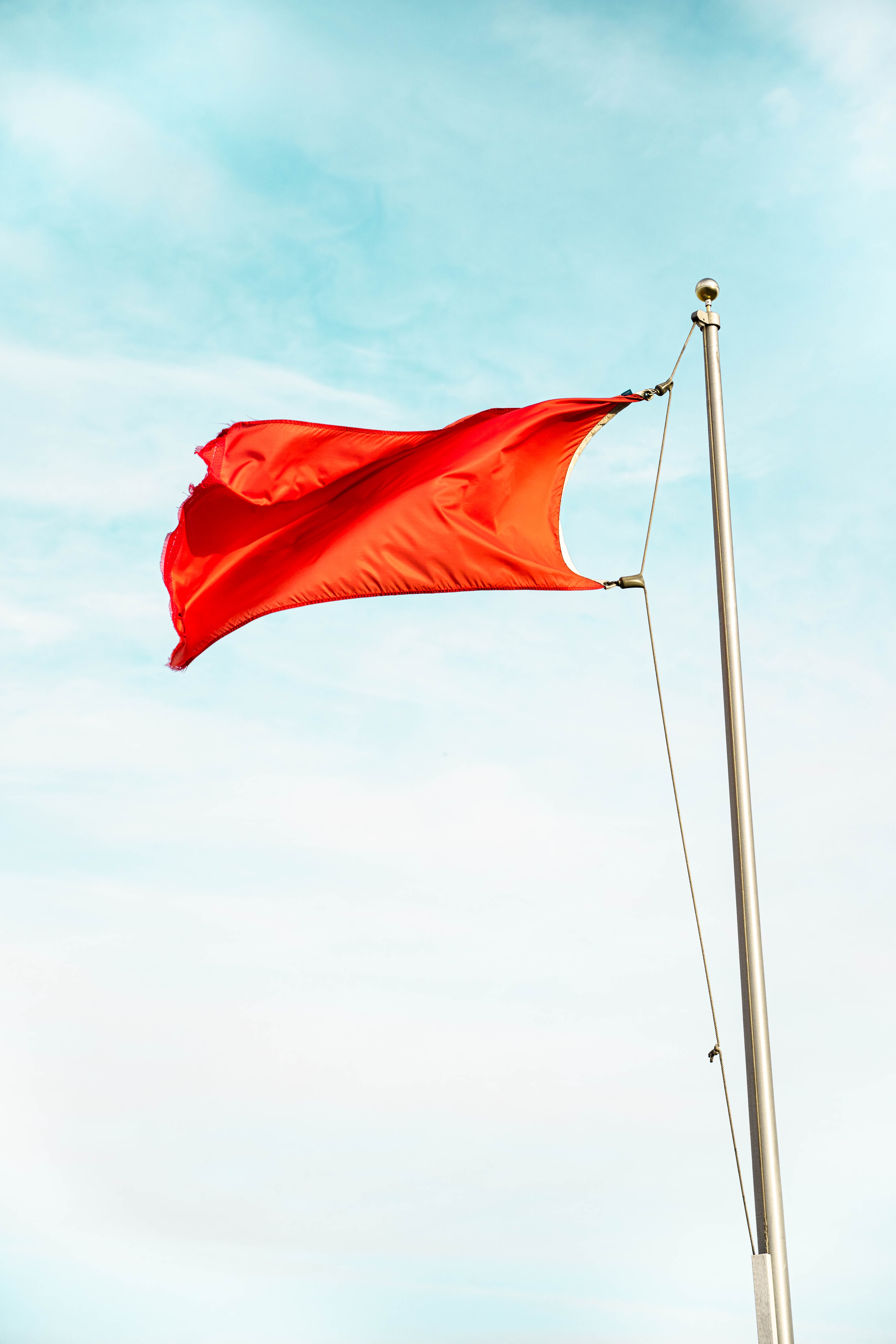 Download wallpaper 4000x6000 flag, red, flagpole, sky hd background