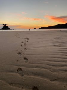 Preview wallpaper footprints, sand, beach, sea, silhouette, sunset