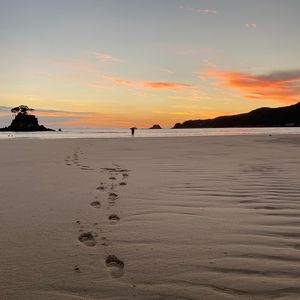 Preview wallpaper footprints, sand, beach, sea, silhouette, sunset