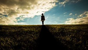 Preview wallpaper girl, field, walking, grass, dark