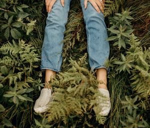 Preview wallpaper girl, legs, jeans, hands, grass