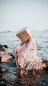 Preview wallpaper girl, mask, sadness, sea, stones