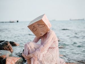 Preview wallpaper girl, mask, sadness, sea, stones