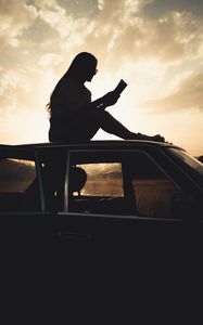 Preview wallpaper girl, reading, books, silhouette, car