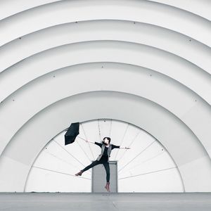 Preview wallpaper girl, umbrella, building, minimalism, jump